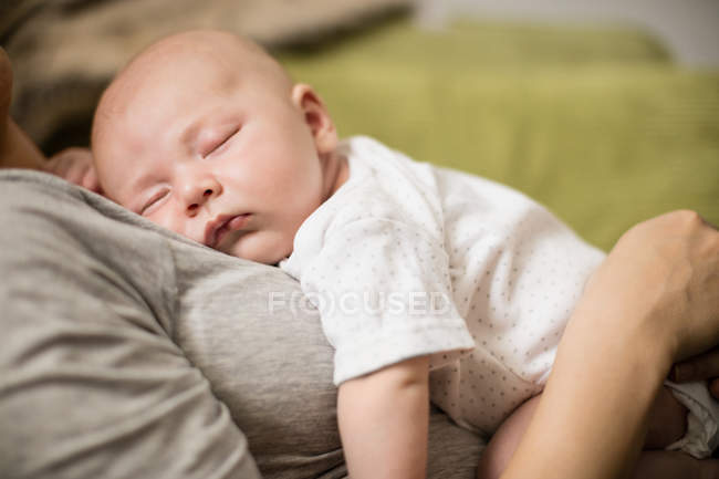 Abgeschnittenes Bild eines niedlichen Babys, das auf Mutter im Wohnzimmer schläft — Stockfoto
