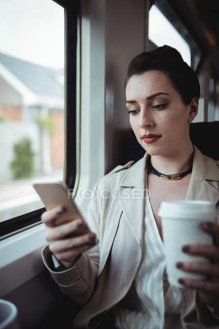 Красива жінка використовує мобільний телефон, сидячи в поїзді — стокове фото