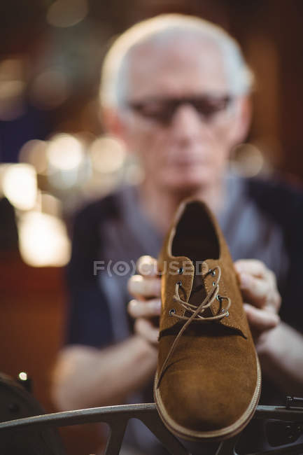 Close-up of shoe and shoemaker using sewing machine in background in workshop — Stock Photo