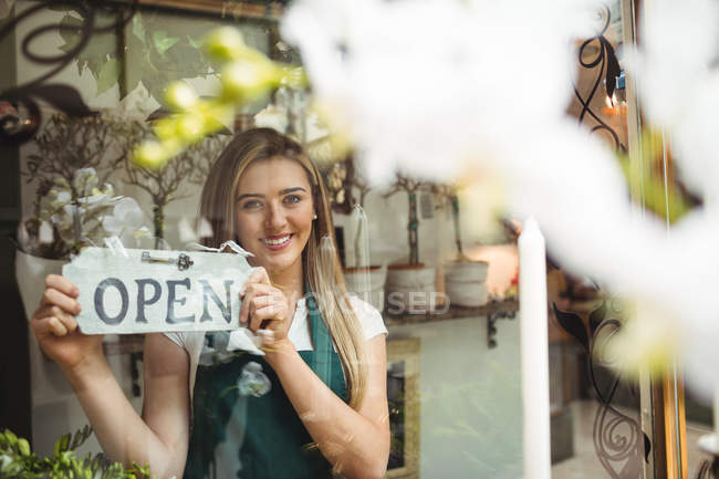 Female florist holding open signboard in the flower shop — Stock Photo