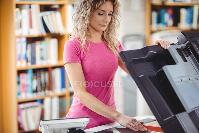 Donna che utilizza fotocopiatrice in biblioteca — Foto stock