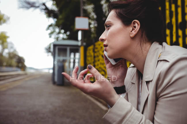 Young woman talking on phone at railroad station platform — Stock Photo