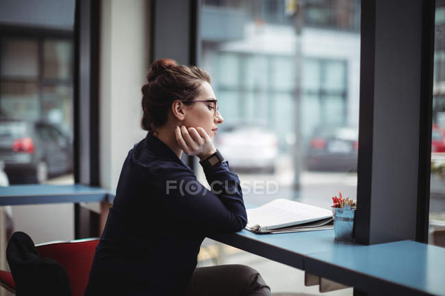 Vista laterale della giovane donna d'affari che legge il giornale nel caffè — Foto stock