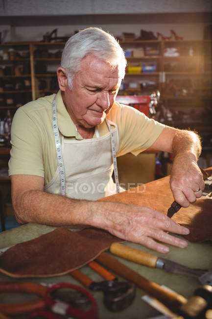 Shoemaker cutting a piece of leather in workshop — Stock Photo
