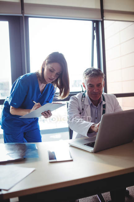 Doctor discussing with nurse over laptop at hospital — Stock Photo