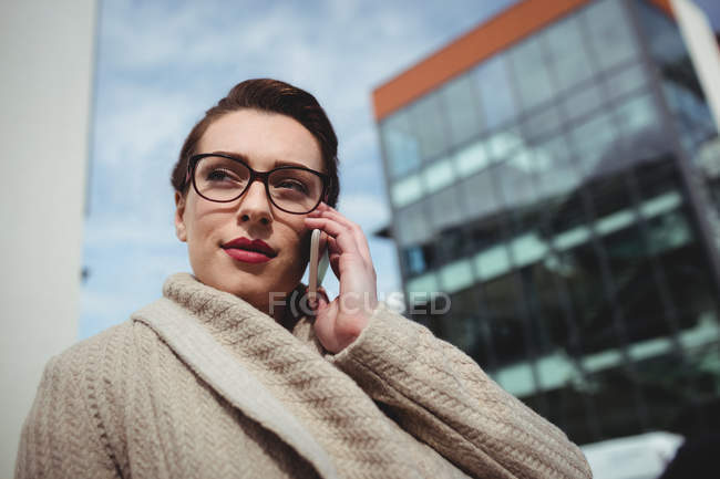Молода жінка розмовляє по телефону, будуючи — стокове фото