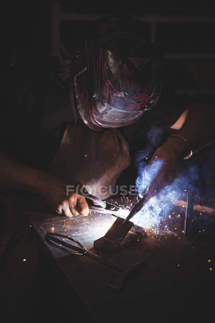 Blacksmith welding a piece of metal in workshop — Stock Photo