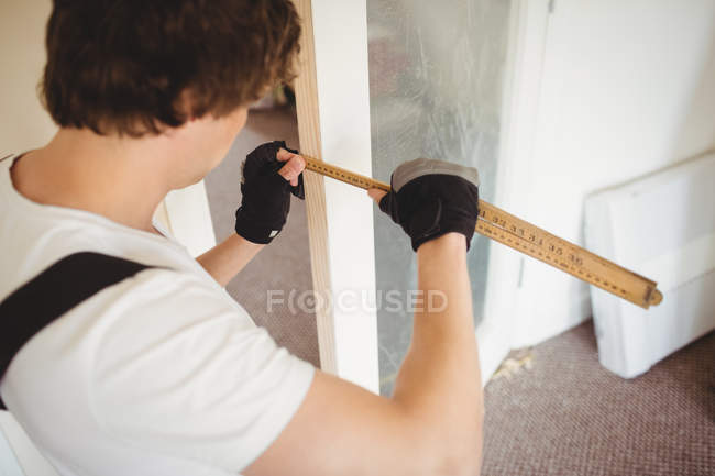 Carpinteiro medindo porta de madeira em casa — Fotografia de Stock