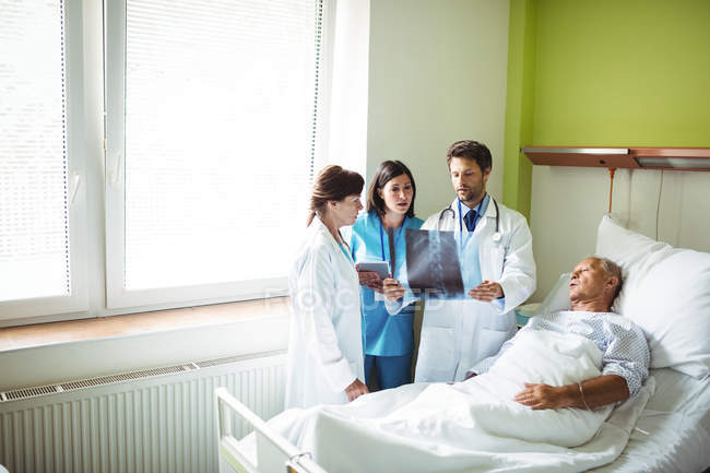 Doctors interacting over x-ray report with patient in hospital — Stock Photo