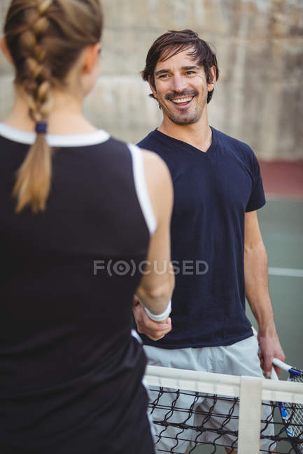 Jogadores de tênis sorridentes apertando as mãos no tribunal antes do jogo — Fotografia de Stock