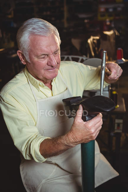 Zapatero haciendo un zapato con martillo en taller - foto de stock