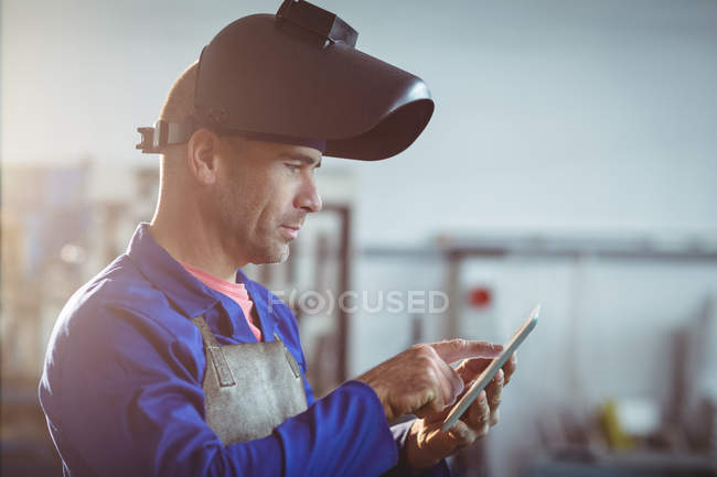 Male welder using digital tablet in workshop — Stock Photo