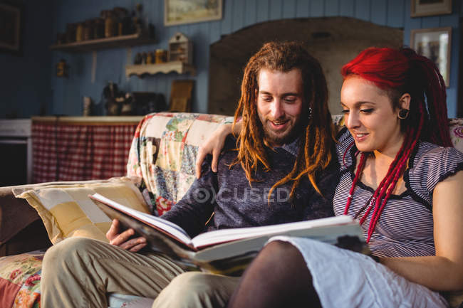 Пара дивиться фотоальбом на дивані, сидячи вдома — стокове фото
