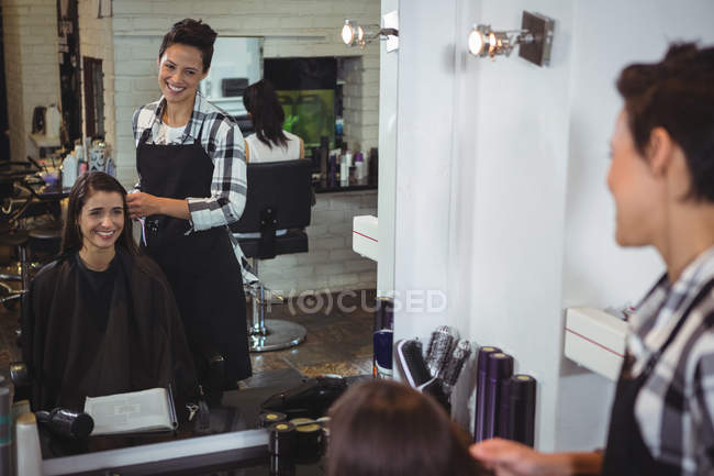 Peluquería sonriente trabajando en cliente en peluquería - foto de stock