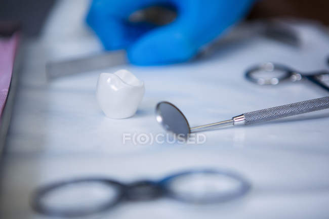 Ferramentas dentárias e dente artificial na bandeja na clínica — Fotografia de Stock