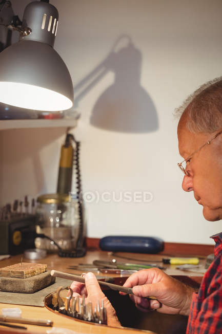 Focused goldsmith preparing ring in workshop — Stock Photo