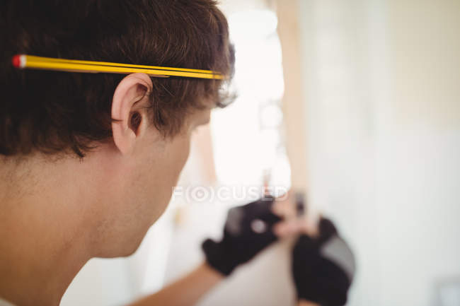 Menuisier avec un crayon sur l'oreille pendant qu'il travaillait à la maison — Photo de stock