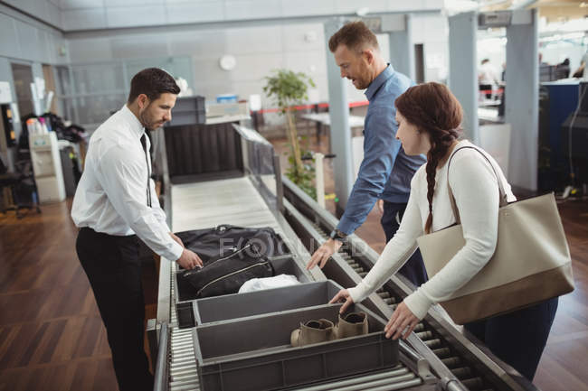 Frau steckt Schuhe für Sicherheitskontrolle am Flughafen in Tablett — Stockfoto