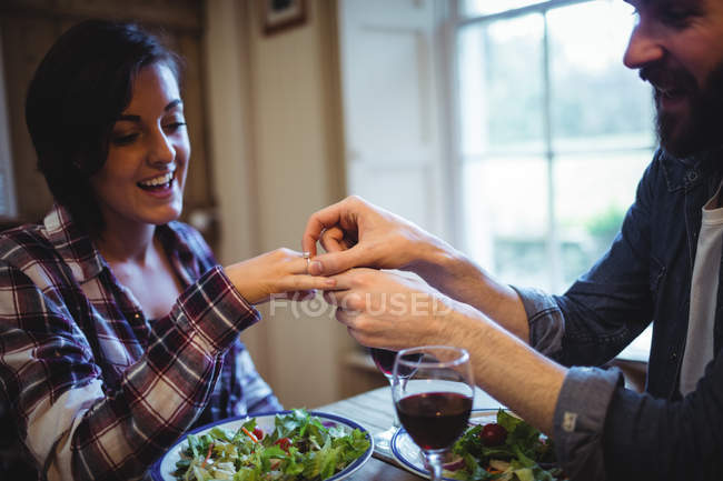 Homem brinde dedo anel para mulher enquanto jantar em casa — Fotografia de Stock