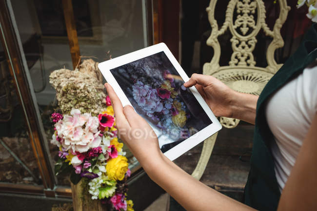 Жіночий флорист фотографує квіти в квітковому магазині — стокове фото