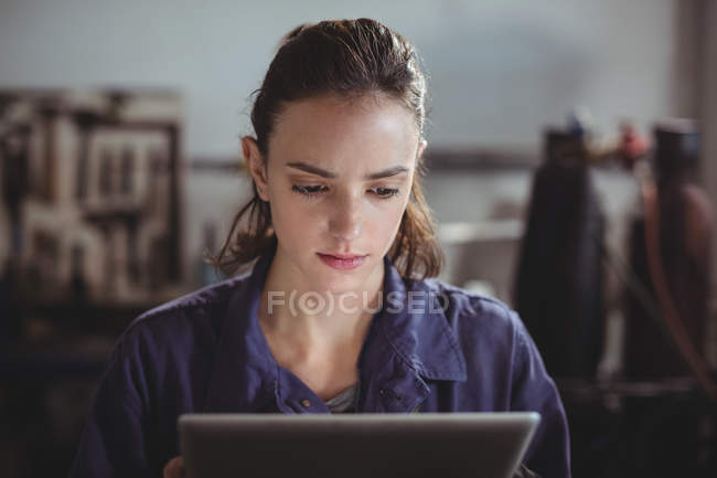 Soldador fêmea segurando tablet digital na oficina — Fotografia de Stock