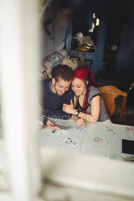 Happy couple using digital tablets seen from window in home — Stock Photo