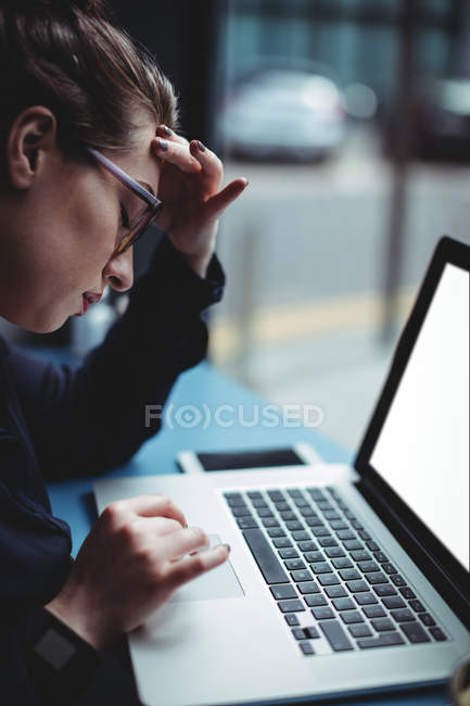Mujer joven ensensed que trabaja en el ordenador portátil en la cafetería - foto de stock