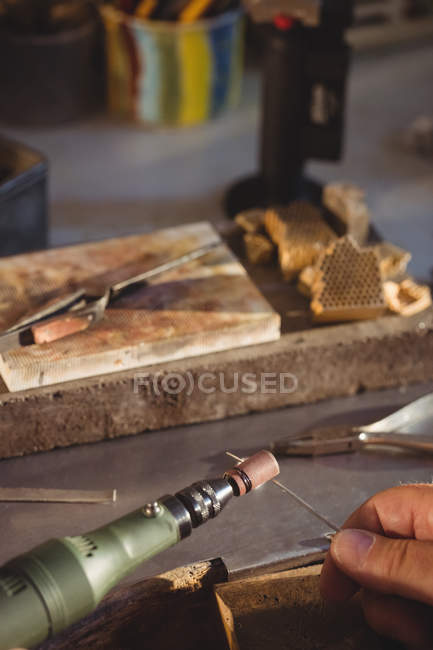 Обрезанное изображение ювелира с помощью ручной машины в мастерской — стоковое фото