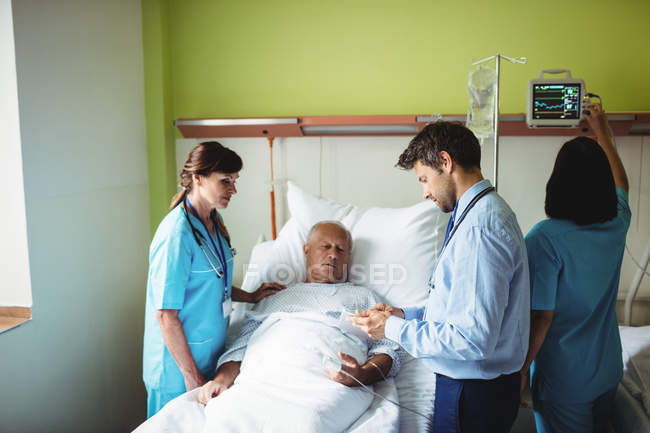 Чоловік-лікар, який показує звіт старшому пацієнту на цифровому планшеті в лікарні — стокове фото
