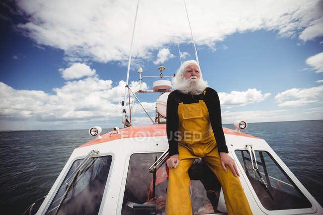 Thoughtful fisherman sitting on deck and looking away — Stock Photo