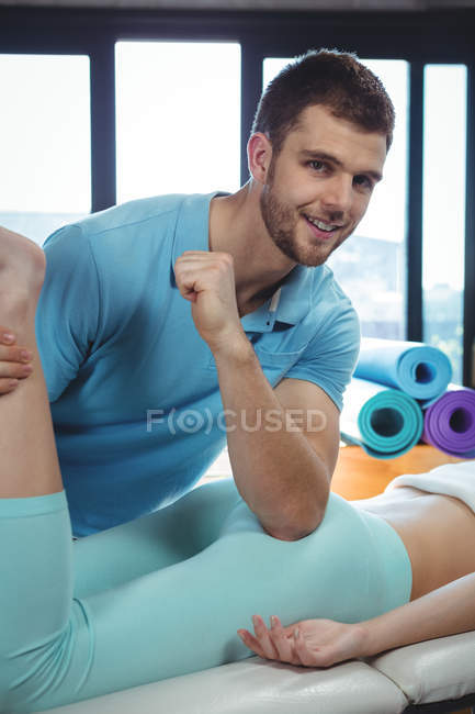 Fisioterapeuta masculino dando masaje de cadera a paciente femenina en clínica - foto de stock