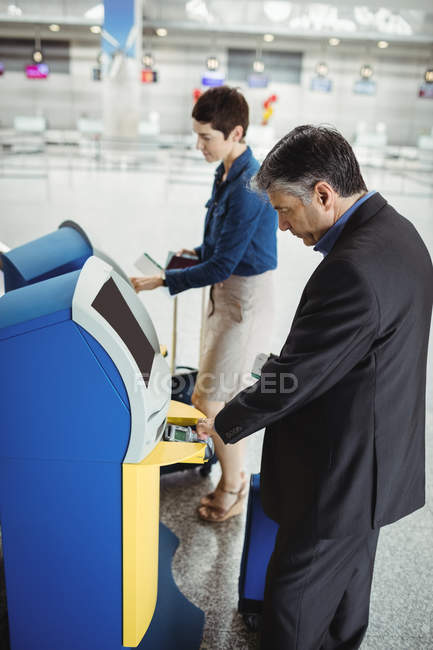 Empresários que utilizam máquinas de check-in self-service no aeroporto — Fotografia de Stock