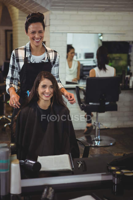 Улыбающаяся женщина-парикмахер работает с клиентом в парикмахерской — стоковое фото