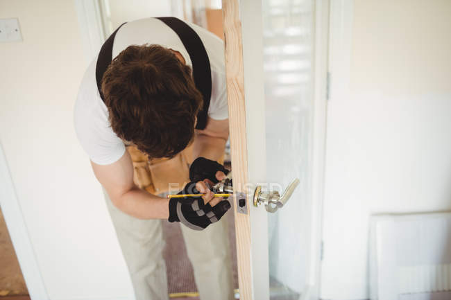 Carpenter fixing door lock at home — Stock Photo