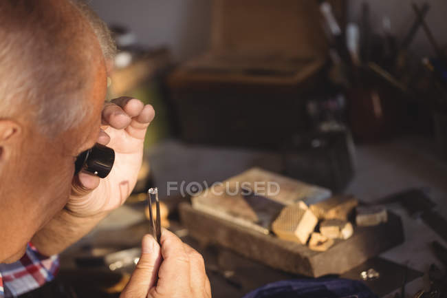 Голкипер изучает алмаз через луп в мастерской — стоковое фото