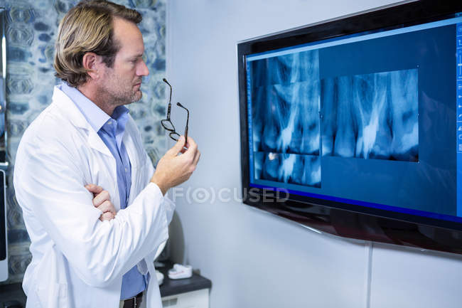 Dentiste réfléchi examinant une radiographie sur le moniteur à la clinique — Photo de stock