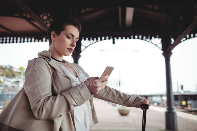 Молодая женщина с помощью мобильного телефона на железнодорожной станции платформы — стоковое фото