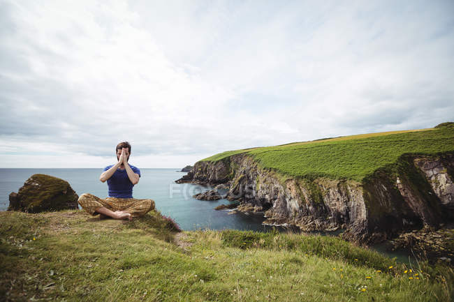 Homme effectuant le yoga sur la falaise — Photo de stock