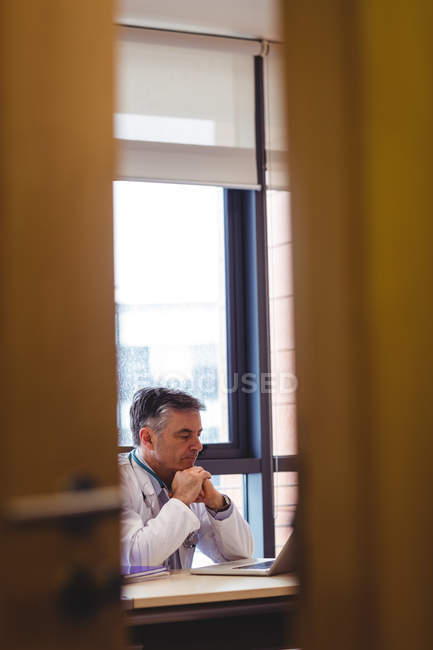 Doctor using laptop at desk in hospital — Stock Photo
