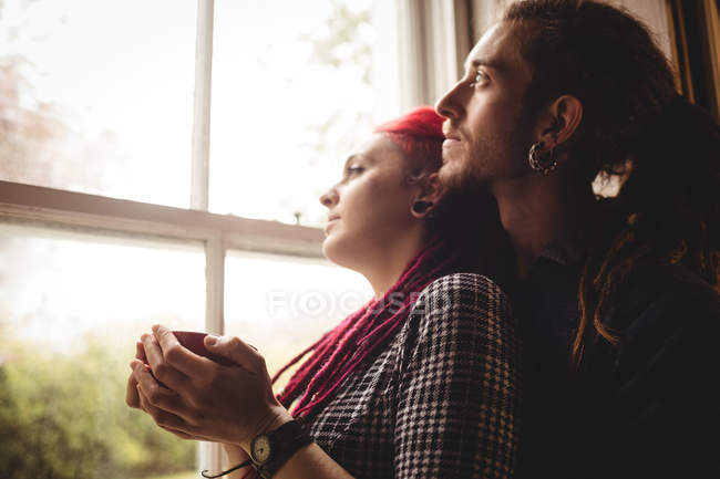 Romantic couple looking through window at home — Stock Photo