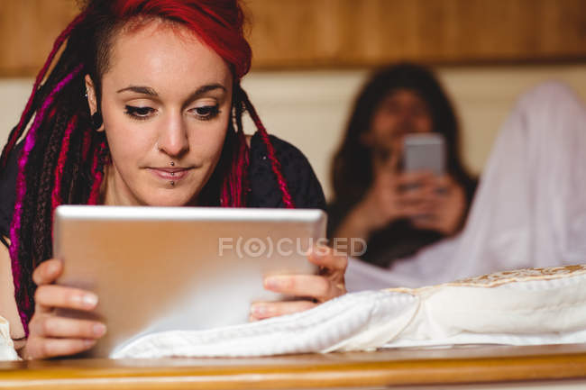 Jeune femme utilisant tablette numérique par l'homme sur le lit à la maison — Photo de stock