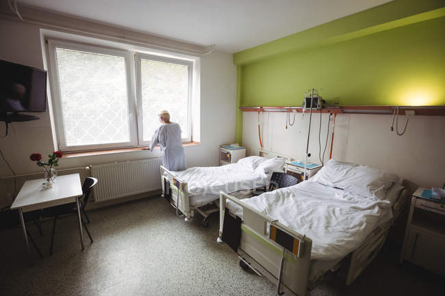 Seniorin steht neben Fenster auf Krankenhausstation — Stockfoto