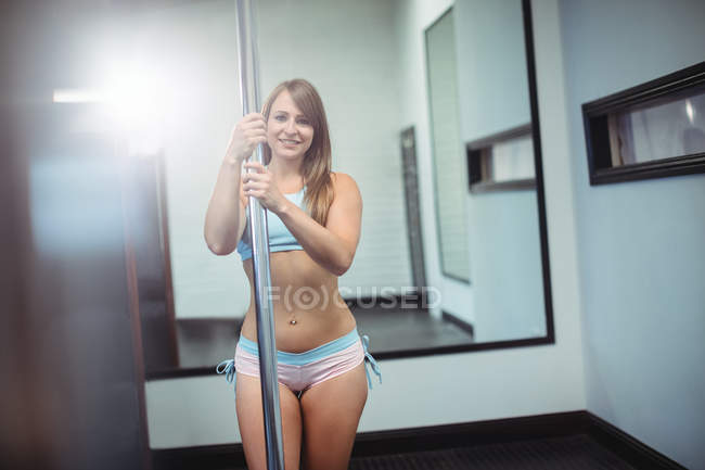 Portrait de la belle pole dancer tenant le poteau dans le studio de fitness — Photo de stock