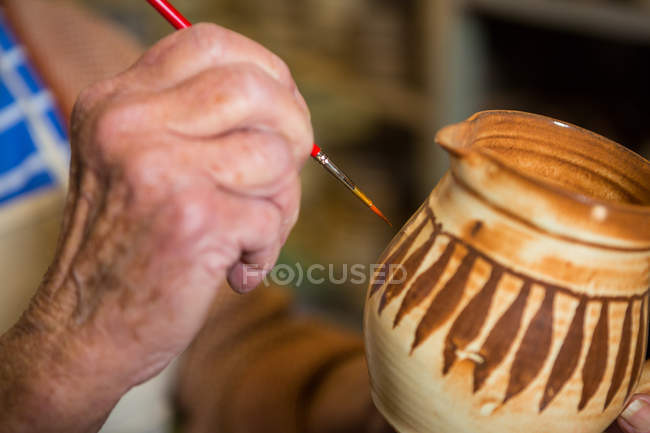 Cropped image of potter painting on bowl in pottery workshop — Stock Photo