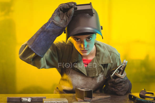 Female welder examining piece of metal in workshop — Stock Photo