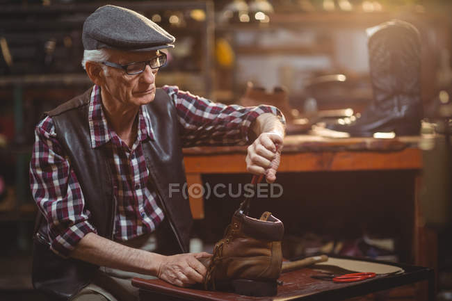 Sapateiro na tampa de reparação de um sapato na oficina — Fotografia de Stock