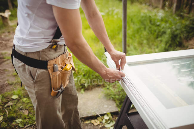 Sección media del carpintero preparando el marco de la puerta en el césped - foto de stock