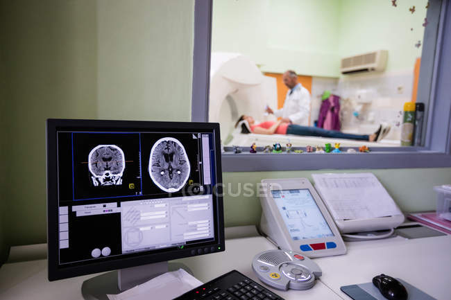 Exploración cerebral digital en el monitor de la computadora con escáner de resonancia magnética en segundo plano - foto de stock