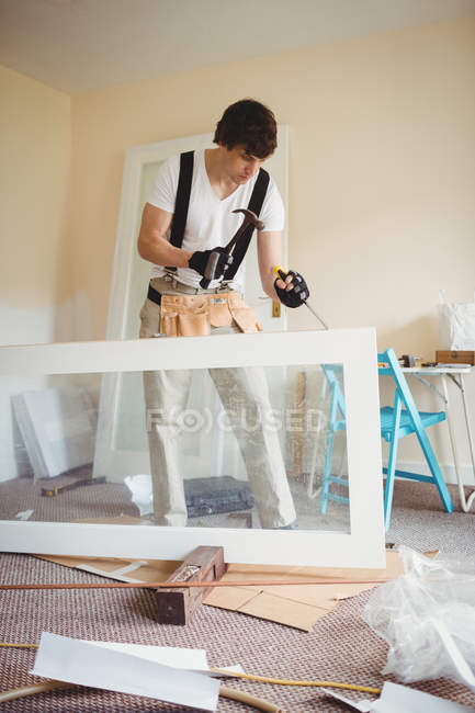 Apuesto carpintero trabajando en la puerta de madera en casa - foto de stock