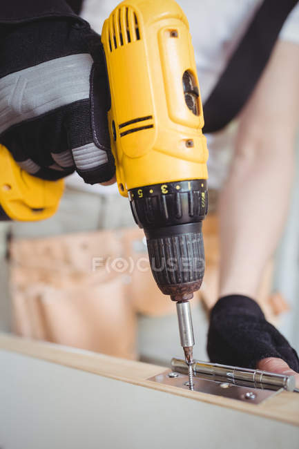 Abgeschnittenes Bild eines Zimmermanns, der zu Hause Schraube an Scharnier an Holztür schraubt — Stockfoto